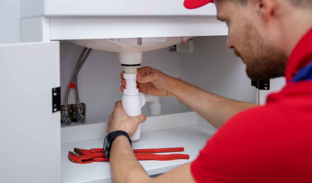 plumber installing sink siphon in domestic bathroom